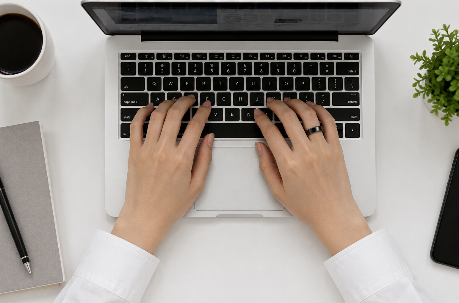 Hands typing on a laptop keyboard, wearing LifeRing on the finger during an ordinary workday